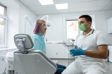 Fototapeta premium male dentist and a female assistant conduct a consultation for a young girl at the reception.