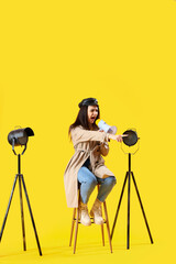 Female film director shouting into megaphone on yellow background