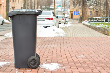 Fototapeta na wymiar View of black garbage container in city on winter day