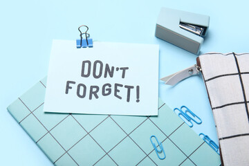 Don't forget reminder with stationery supplies on blue background, closeup