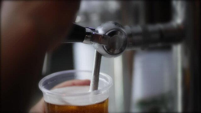 Hand of bartender pouring a large lager beer in tap, slow motion