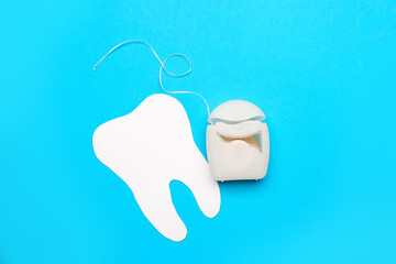 Case with dental floss and model of tooth on blue background