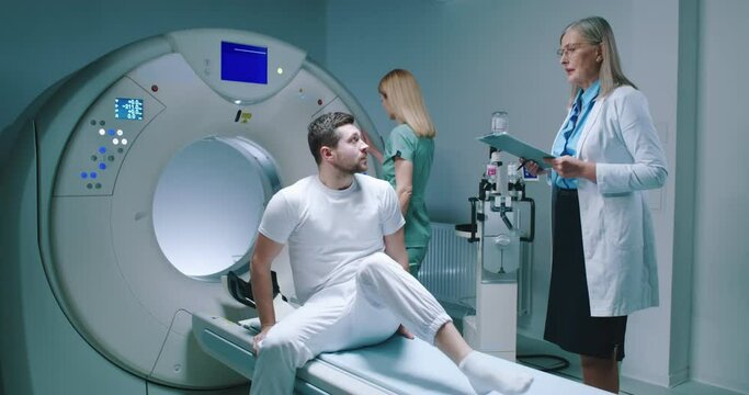 Male patient is waiting to be scanned. Man have talk with female doctor. Nurse is preparing for performing of magnetic resonance tomography. Patient is getting ready for MRI examining.