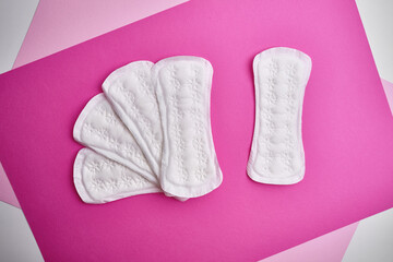 Women's pads and tampon. Sanitary pads lie next to a tampon on an isolated background on a pink and white background. The concept of health, feminine hygiene and the menstrual cycle