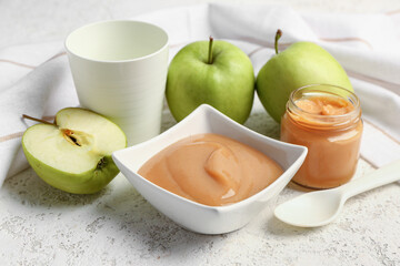 Bowl of healthy baby puree and fresh apples on light background