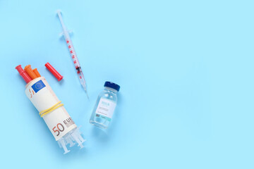 Insulin with syringes and money on blue background. Expensive medicine concept