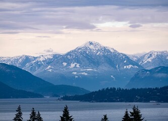 View of a lake with snowcap mountains in the background under blue cloudy sky in Vancouver