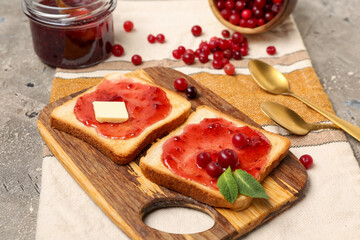 Wooden board of tasty toasts with cranberry jam on grunge background