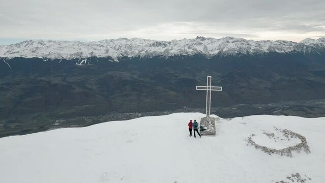Drone footage filming Dent de Crolles mountain with snowy ridged and h a Christian cross