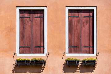 Close up detail with old medieval architecture venetian window. Closed wooden shutters.