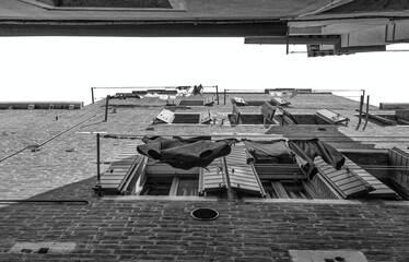 Fototapeta na wymiar Clothes laundry left to dryat the window of a old medieval building in Venice, Italy. Black and white street photography