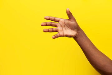 empty hand of african american man on yellow isolated background, handshake gesture, the guy shows the palm