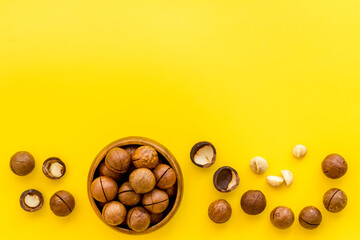 Flat lay of macadamia nuts in bowl, top view. Healthy food background