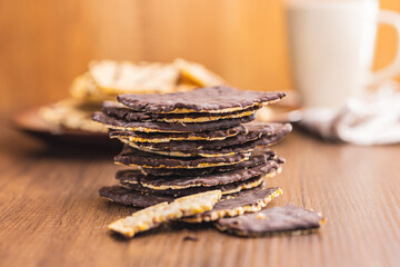 Puffed corn crackers chocolate covered on wooden table.