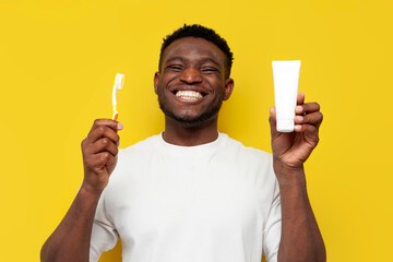african american man with white toothy smile holds toothbrush and tube of toothpaste