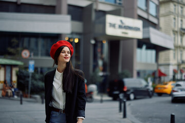 Woman smile with teeth tourist walks walks in the city on the background of office buildings, stylish fashionable clothes and make-up, spring walk, travel.