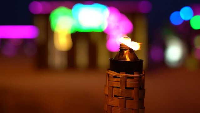 A burning torch at night on the beach against the backdrop of a bar close-up.