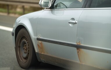 Car that started rusting. European old car on the highway. Rusty vehicle. Weathered car body that...