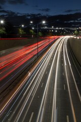 Fototapeta na wymiar Light trails from speeding cars on the A40 highway in Perivale, London, UK, during the early evening