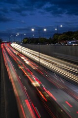 Fototapeta na wymiar Light trails from speeding cars on the A40 highway in Perivale, London, UK, during the early evening