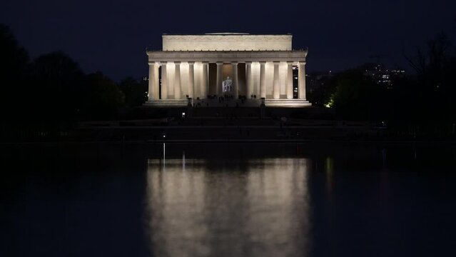 Illuminated Lincoln Memorial reflected in the waters of a pond during the dark nighttime