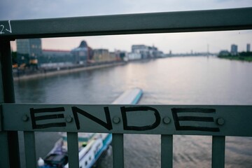 the word ende is written on the railing. In the background is a ship on the river.