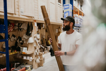 A young handsome man with a beard in casual clothes in a construction hypermarket in the lumber...