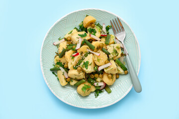 Plate of tasty Potato Salad with vegetables on blue background