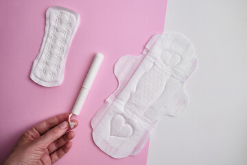 Women's pads and tampon. Sanitary pads lie next to a tampon on an isolated background on a pink and white background. The concept of health, feminine hygiene and the menstrual cycle