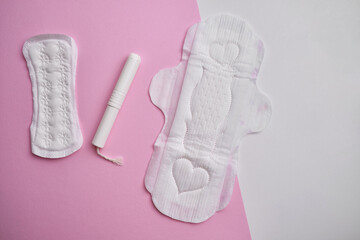 Women's pads and tampon. Sanitary pads lie next to a tampon on an isolated background on a pink and white background. The concept of health, feminine hygiene and the menstrual cycle