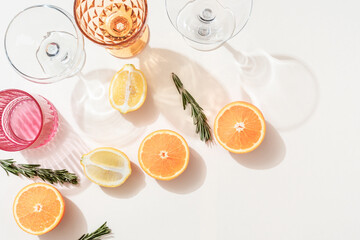 Summer orange cocktails with citrus fruits on white background. Hard seltzer, lemonade, refreshing drinks, low alcohol mocktails, summer party concept. Trendy palm leaf shadow and sunlight, sun.