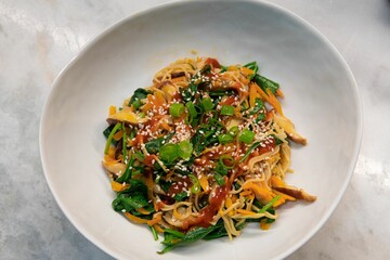 High-angle shot of a traditional Thai dish with onion, sauce and noodles