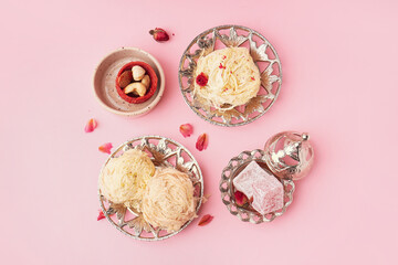 Plates with tasty Turkish Pismaniye and delight on pink background