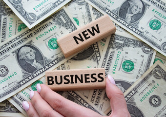 New business symbol. Concept words New business on wooden blocks. Businessman hand. Beautiful dollar background. Business and New business concept. Copy space.