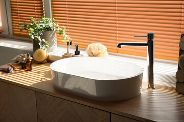 Sink with bath accessories on table near window in room