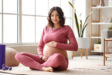 Sporty pregnant woman sitting at home - obrazy, fototapety, plakaty