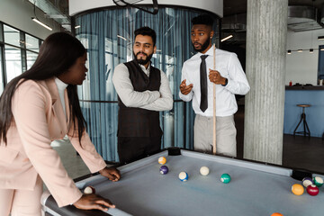 Young multiracial people in suits playing pool at office lobby