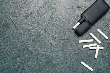 Modern electronic cigar with sticks on dark grunge table