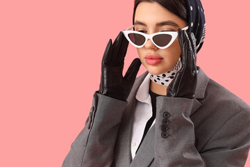 Stylish young woman in sunglasses and leather gloves on pink background, closeup