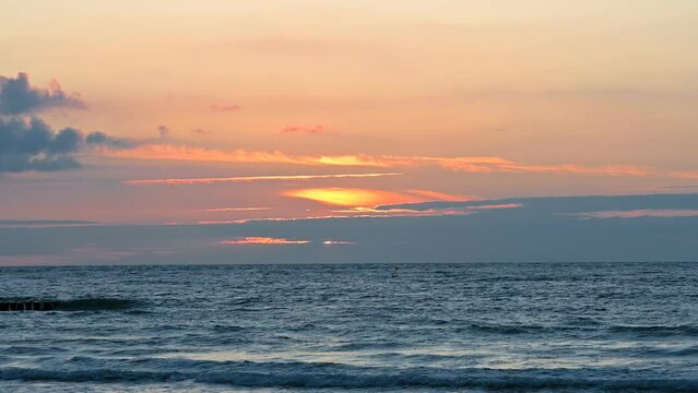 Scenic view of calm sea waves with a peach sunset in the background