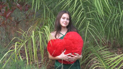 St. Valentine's Day concept. Girl with large red heart in nature