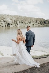 Vertical shot of a beautiful bride and groom standing together on a lake shore