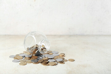 Overturned jar with coins in beige grunge table. Savings concept