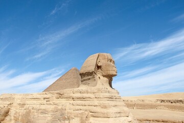 Ancient Egyptian pyramids and the Great Sphinx of Giza against a blue cloudy sky on a sunny day