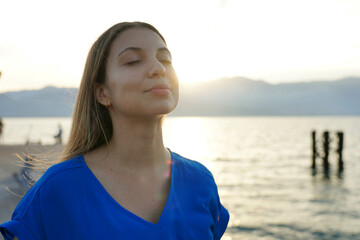 Portrait of meditative woman breathing on sunset. Spirituality, purity and peace concept.