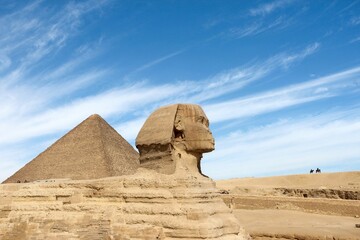 Ancient Egyptian pyramids and the Great Sphinx of Giza against a blue cloudy sky on a sunny day