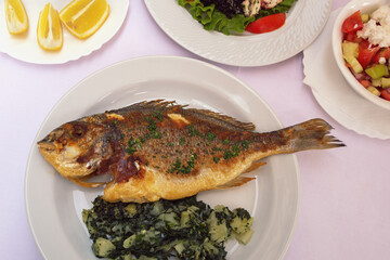 Balkan cuisine. Grilled fish ( sea bream ) with green leafy vegetables on white plate