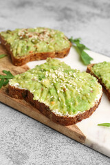 Board of tasty avocado toasts on light background