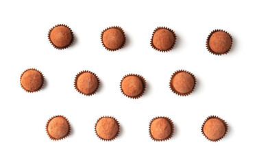 Chocolate truffles in individual paper baskets on a white background, top view.