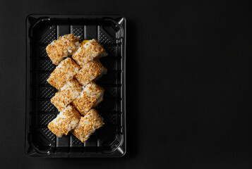 Sushi rolls in a package on a black background, top view.